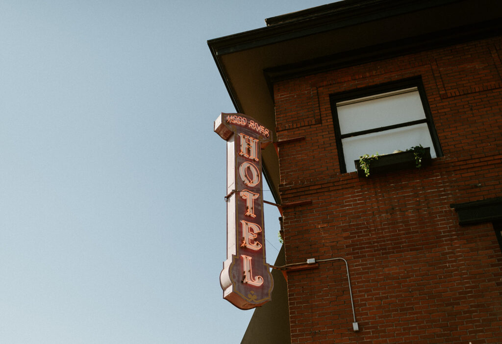 A hotel sign hangs from the side of a brick building