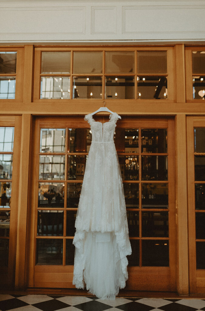 A wedding dress is hanging on a door in a room.