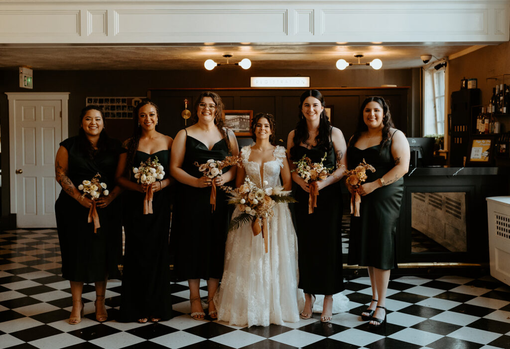 A bride and her bridesmaids are posing for a picture in a room with a checkered floor.