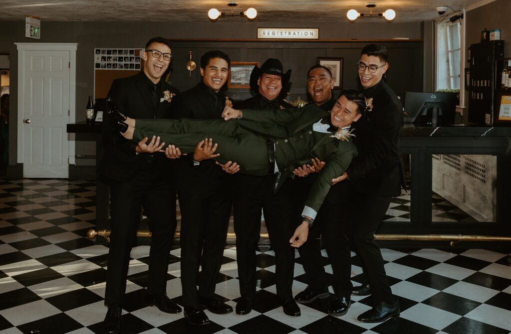A group of men are holding the groom in their arms.