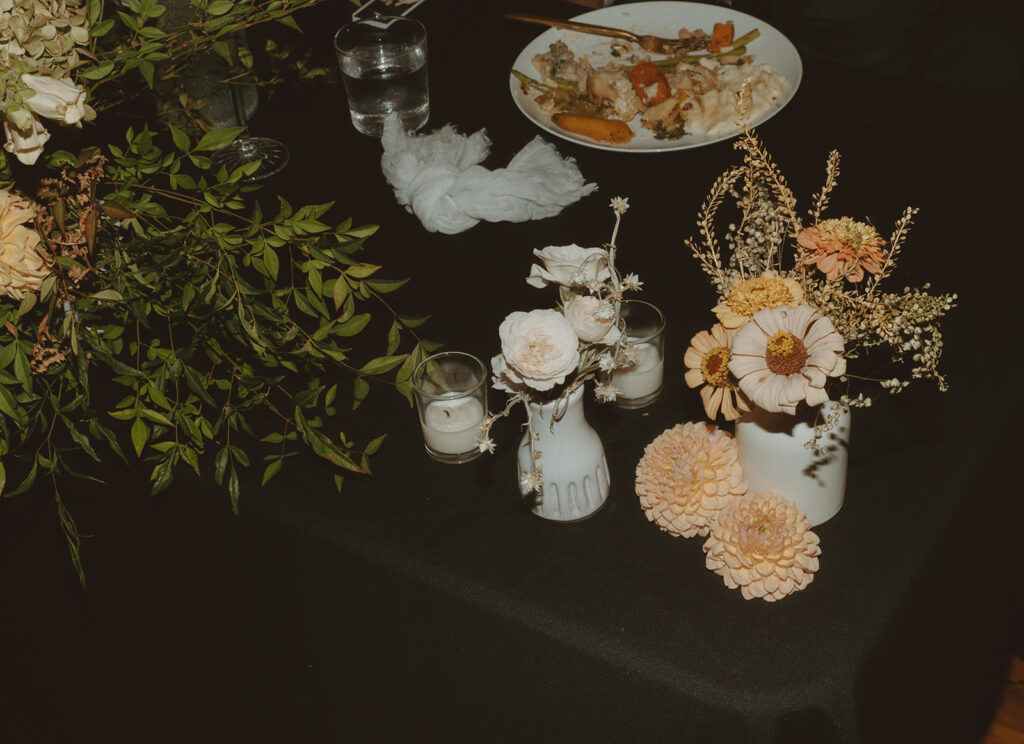 A table with flowers, candles, and a plate of food on it.