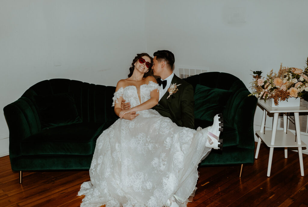 A bride and groom are sitting on a green couch.