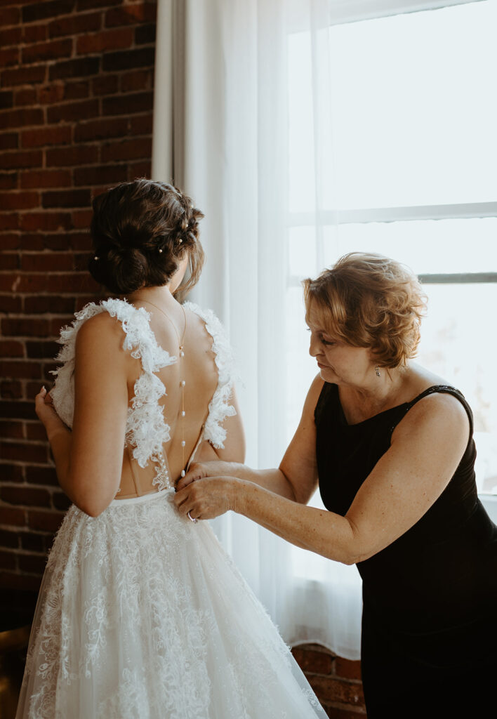 A woman is helping a bride get ready for her wedding.