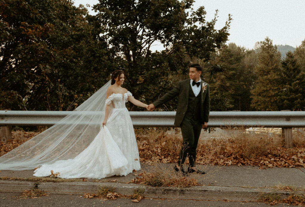 A bride and groom are walking down the street holding hands.