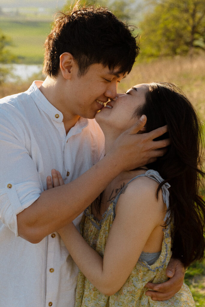Couple sharing a joyful kiss in a sunlit field