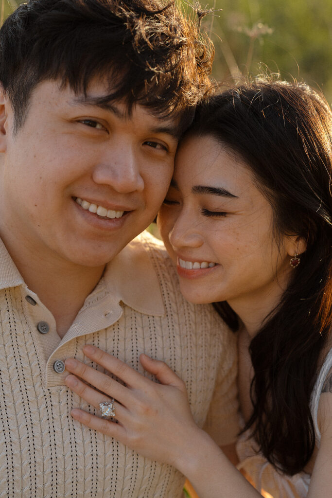 Close-up of couple smiling and cuddling, showing engagement ring