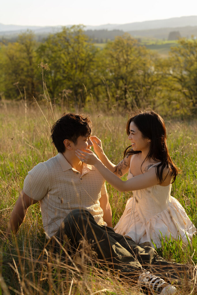 Woman touching her partner’s face as they sit in a field