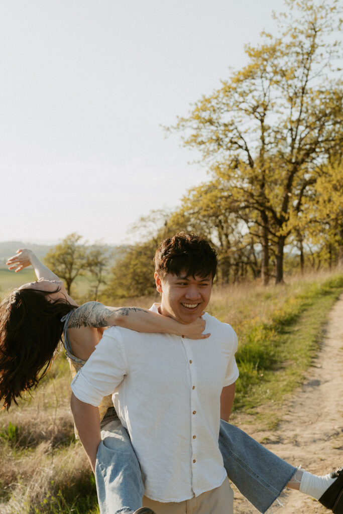 Man giving his partner a piggyback ride on a sunny trail