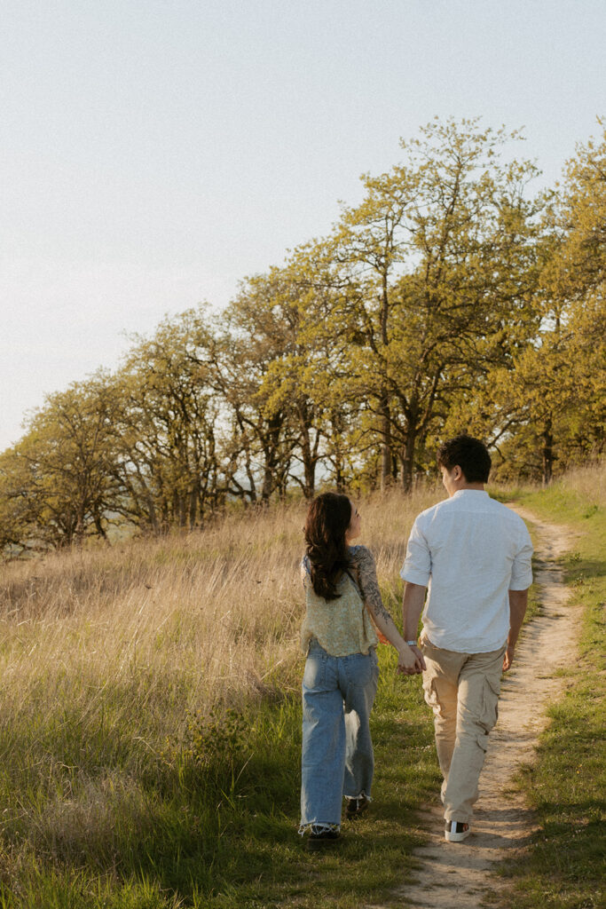 Couple holding hands while walking on a path through tall grass