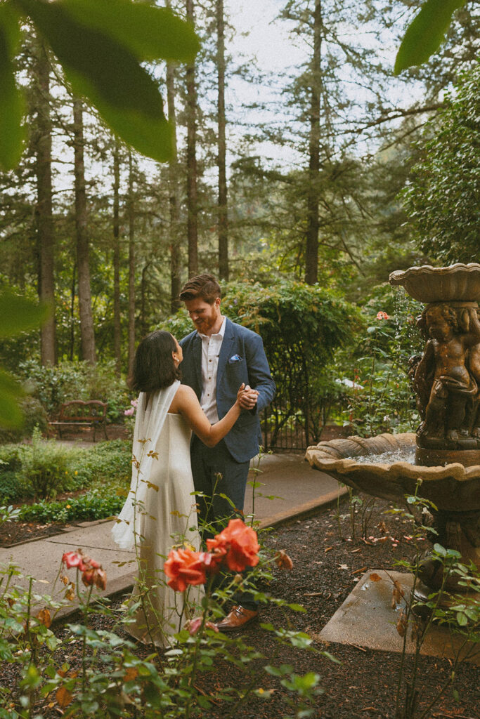 Couple dances near a fountain surrounded by roses