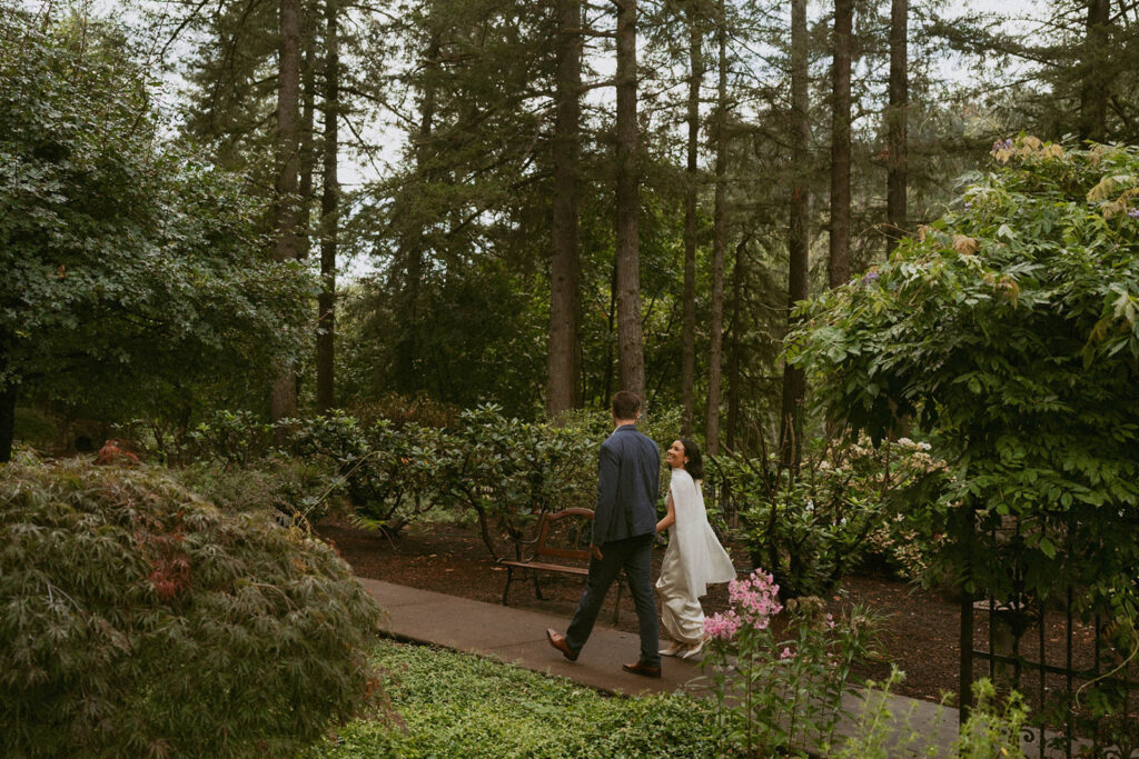 Bride and groom laugh together on a garden path
