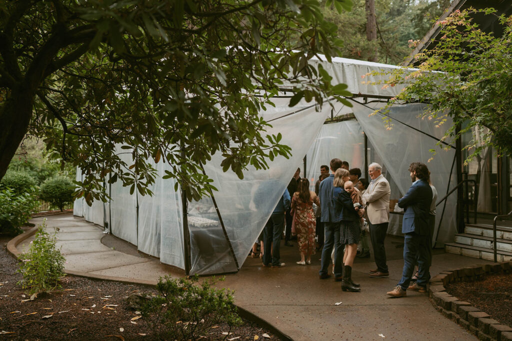Guests gather outside a clear wedding reception tent