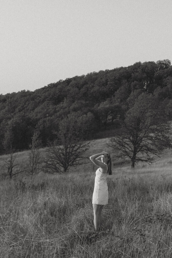Black and white image of a woman standing in a grassy field looking up