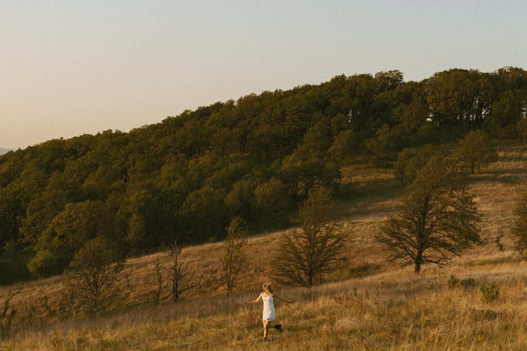 Girl walking through tall grass toward scenic countryside view