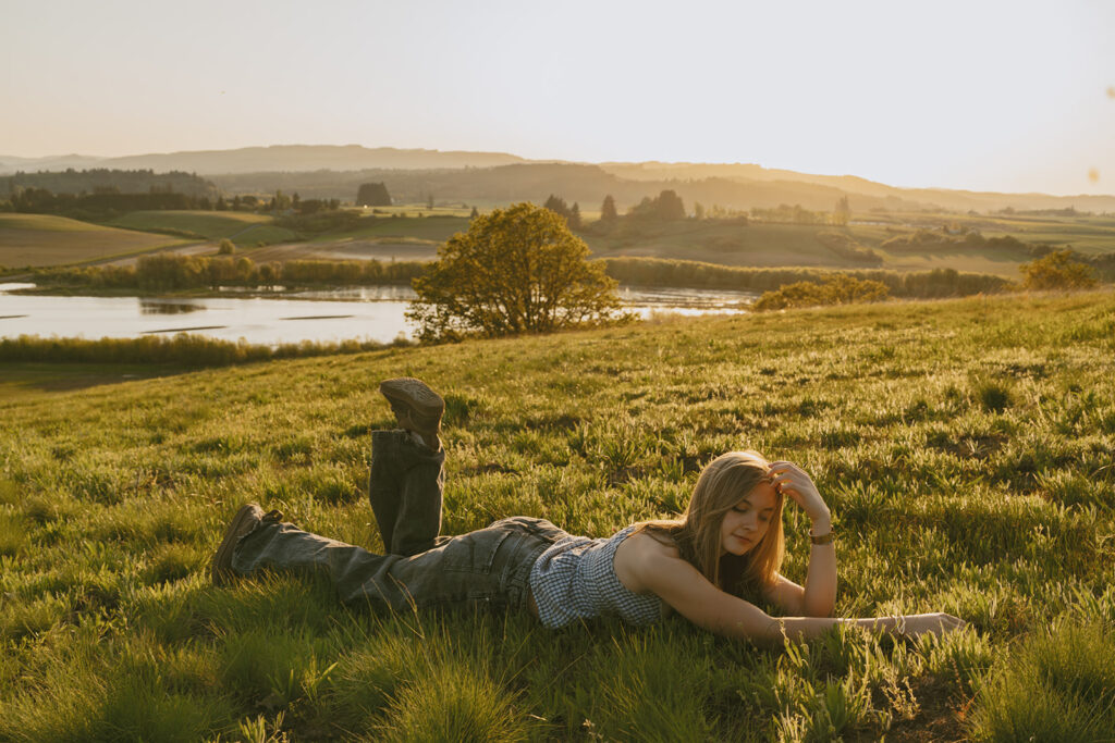 Woman lying in the grass with her hand in her hair, eyes closed in sunlight