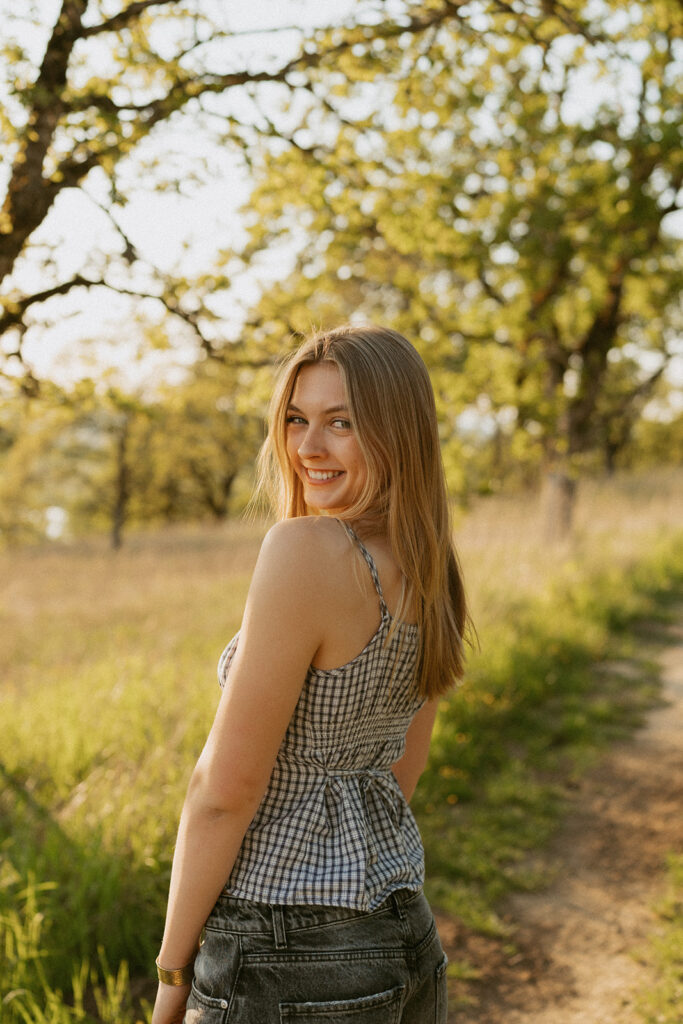 Smiling girl looking over shoulder in a sunlit field