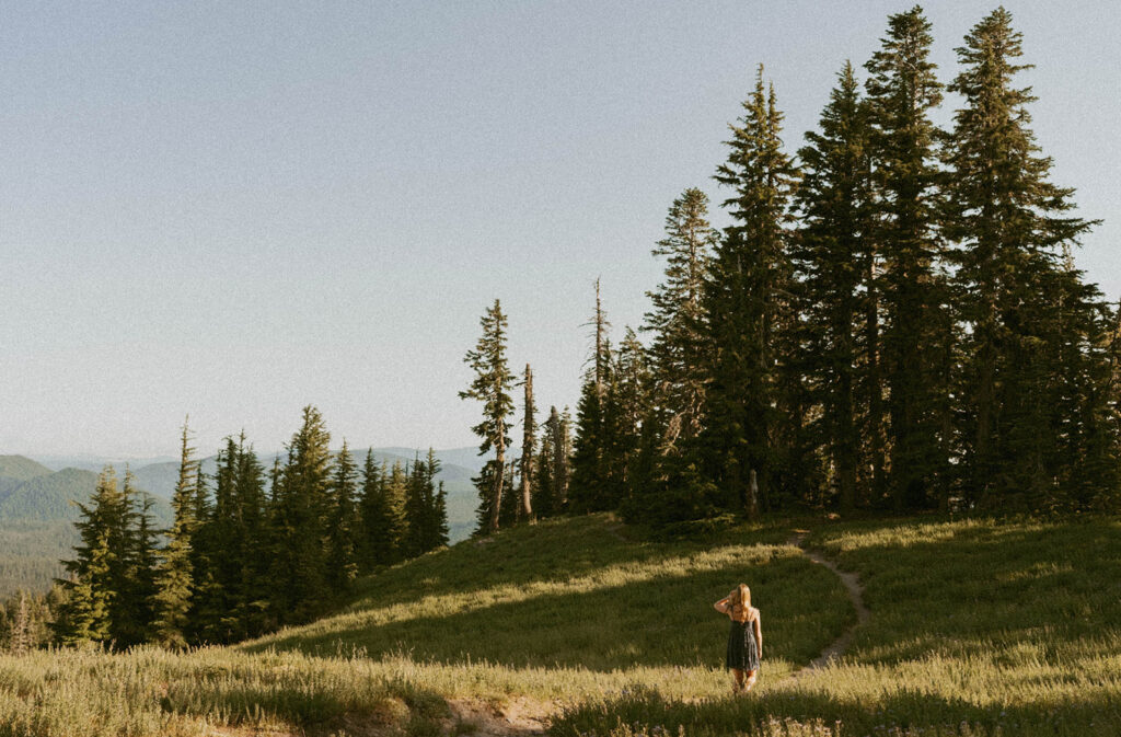 A woman is standing in a field with trees in the background