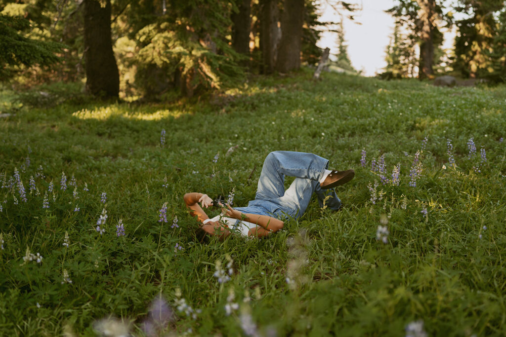 A person is laying on their stomach in a field of flowers.