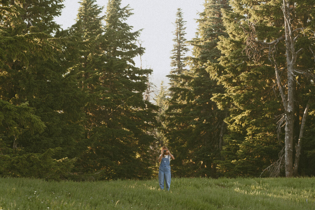 A person standing in a field with trees in the background