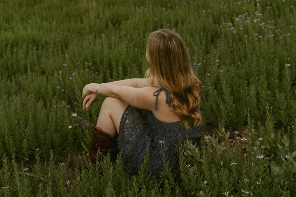 A woman is sitting in the grass in a field.