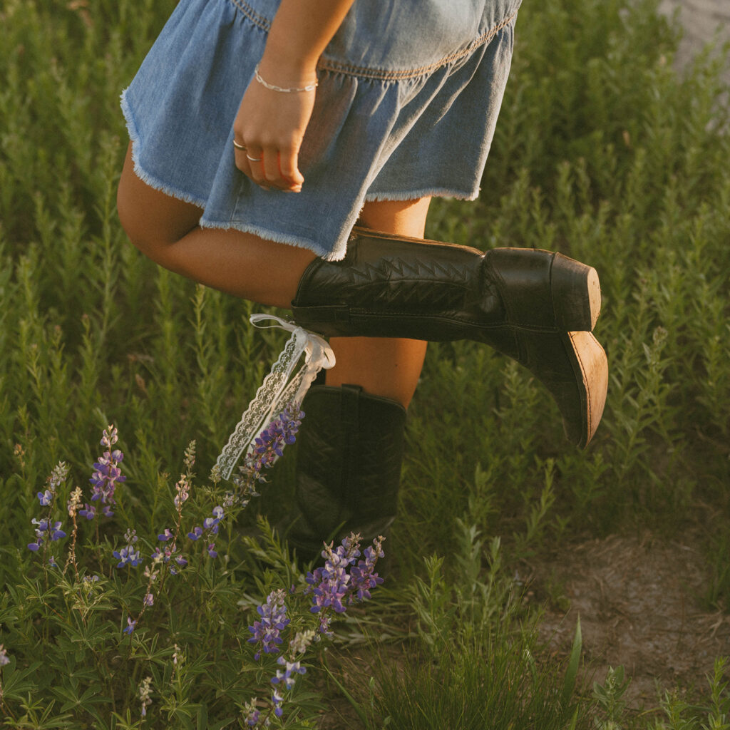 A woman wearing a denim skirt and black cowboy boots