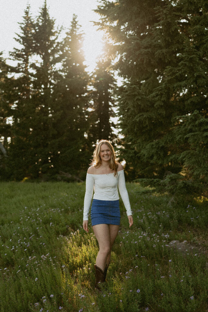 A woman is standing in a field of grass with trees in the background.