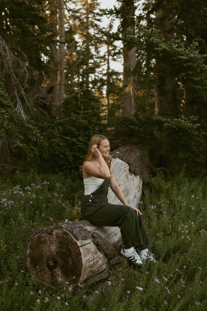A woman is sitting on a log in the middle of a forest