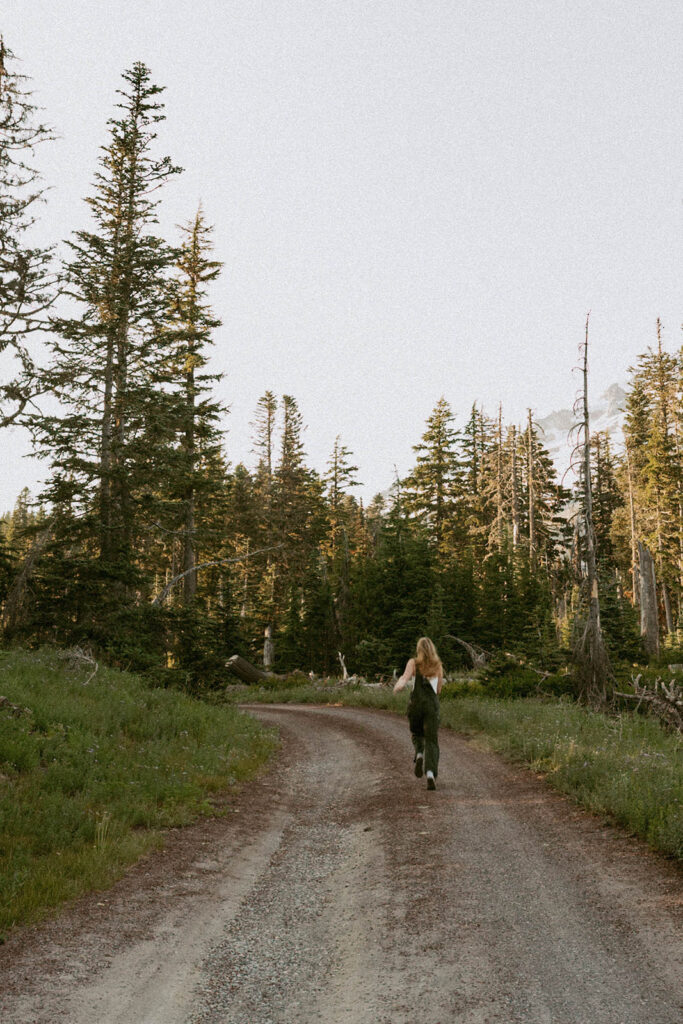 A senior is running down a dirt road in the woods.
