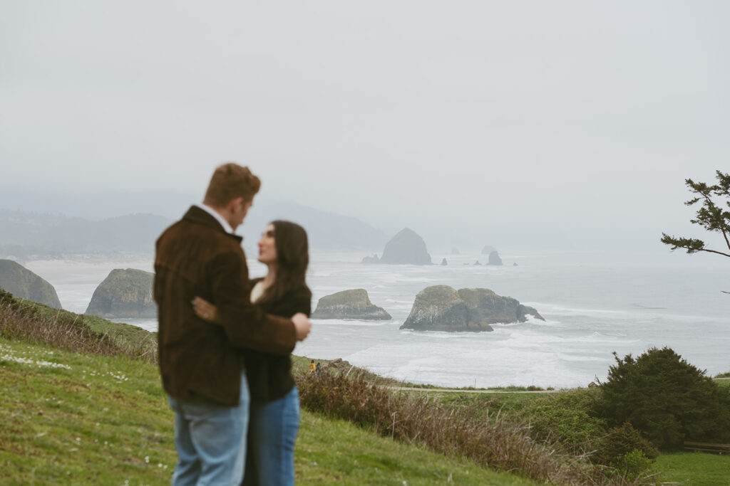 Couple embracing with coastal sea stacks in the background