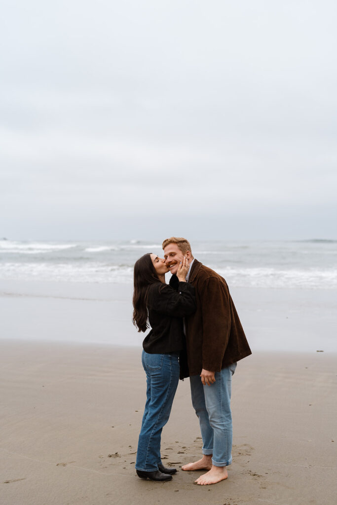 Couple smiling and embracing barefoot on the beach