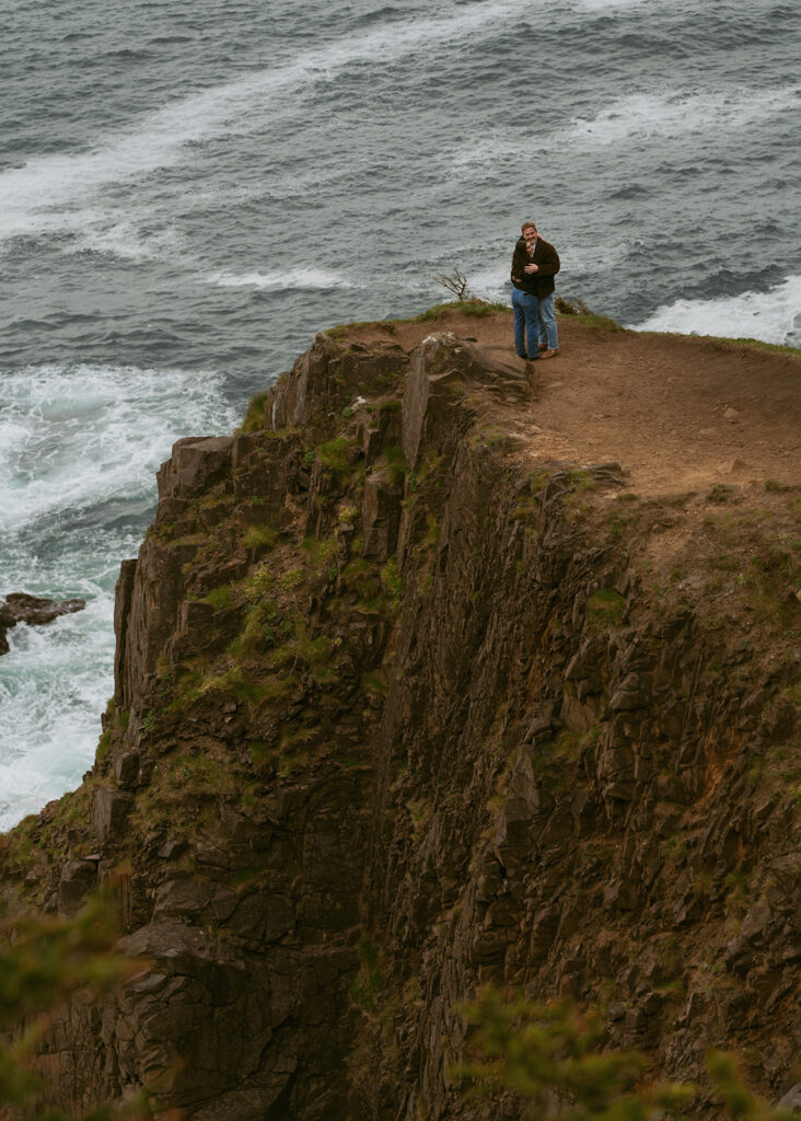 Couple embracing on a rocky cliff above the sea for a beach proposal
