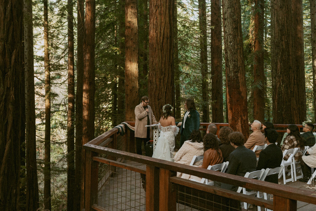 Wedding ceremony with guests seated on a redwood deck in the forest
