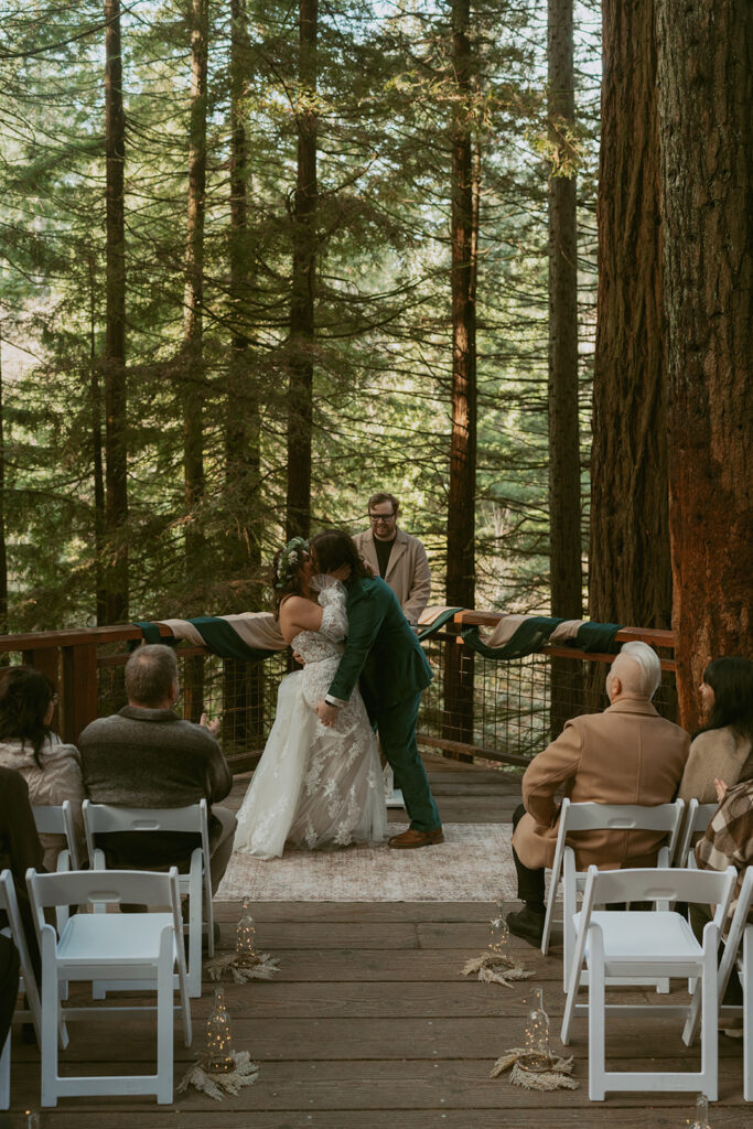 Couple shares their first kiss as newlyweds in a redwood forest ceremony at Hoyt Arboretum