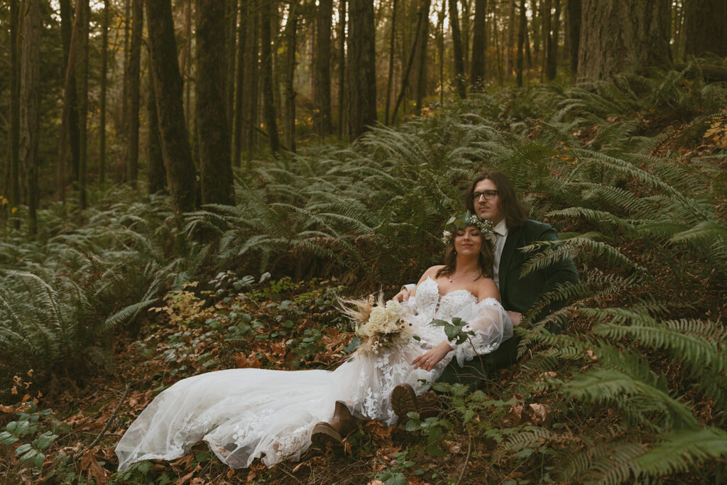 Newly Wed sitting down in a forest setting surrounded by trees