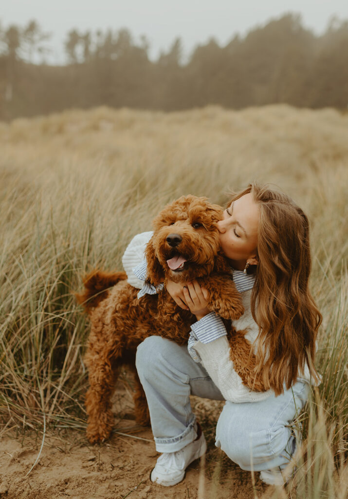 Woman hugs fluffy dog in golden grass in Portland