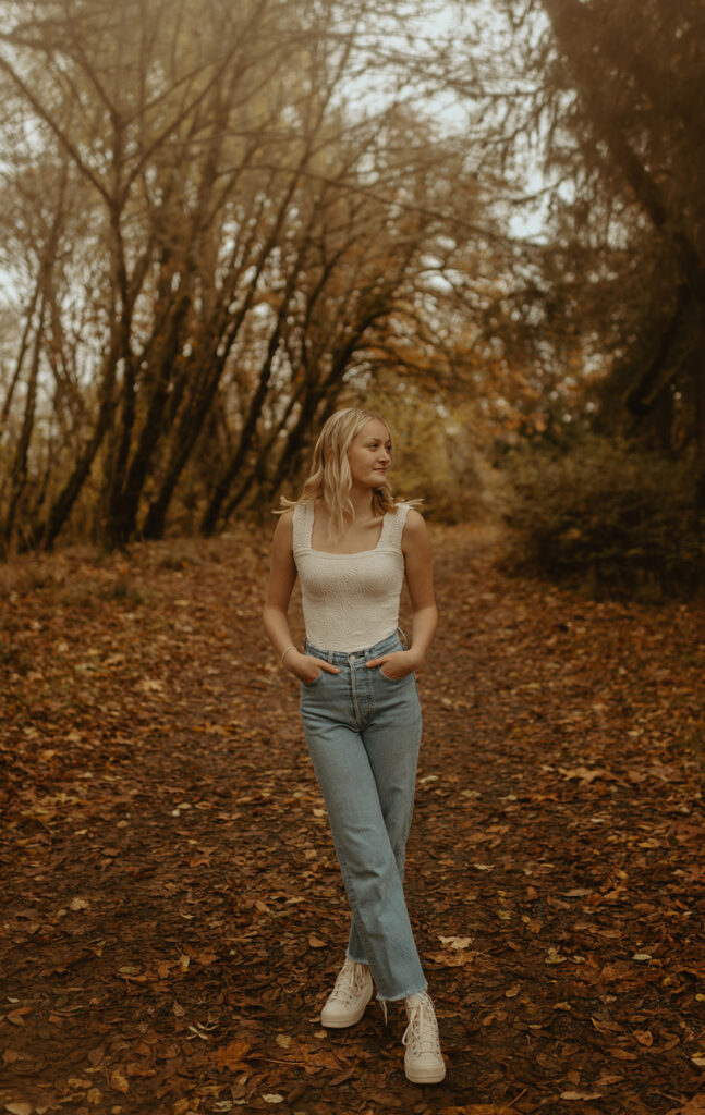Blonde woman stands among autumn trees in Oregon
