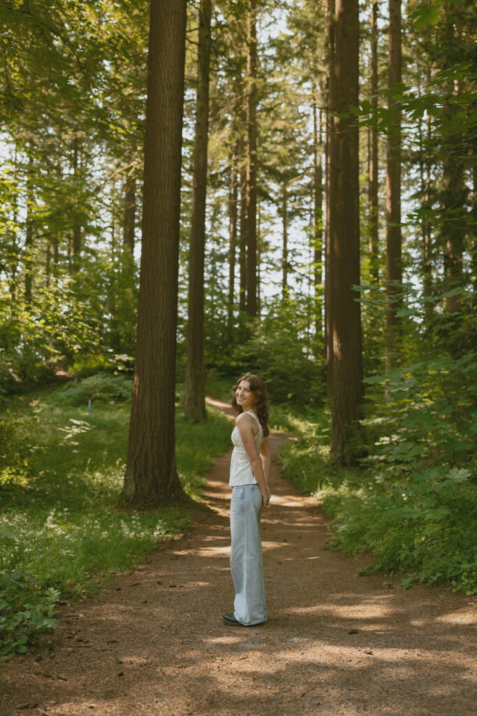 High school senior walks forest path in dappled sunlight in Portland 

