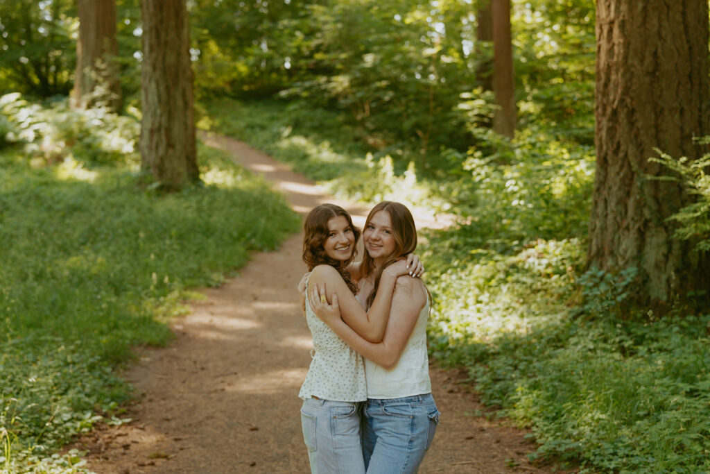 Two high school senior students embrace on forest path in Portland