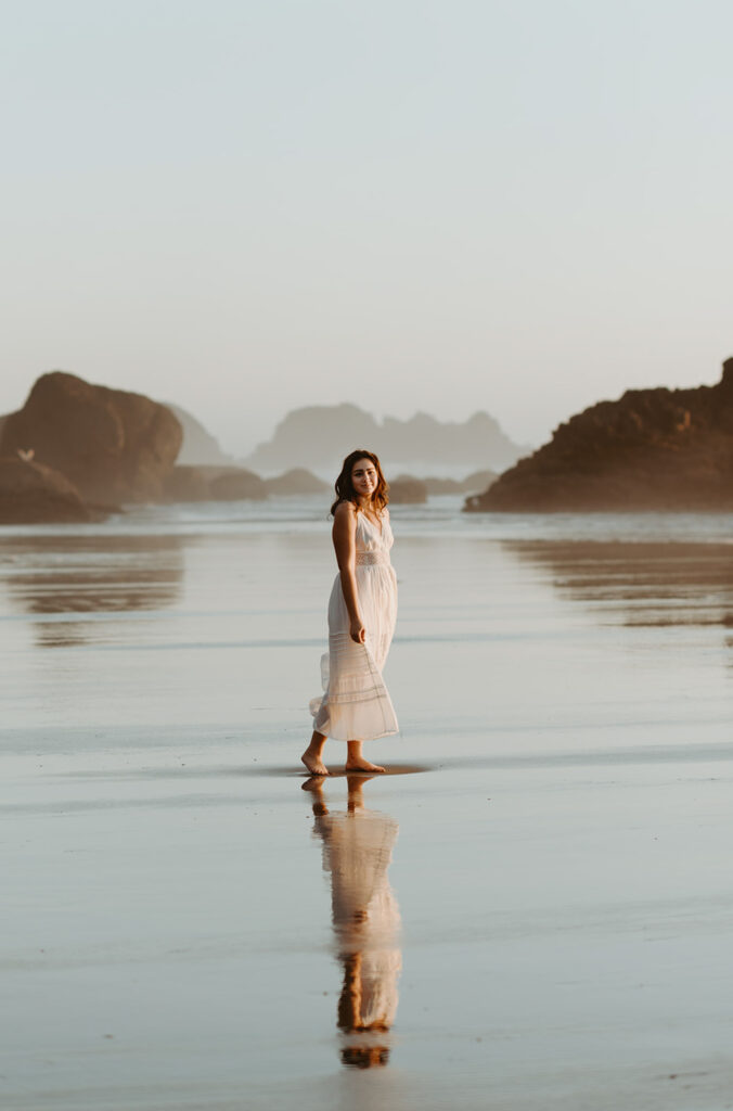 Woman on reflective beach at sunset