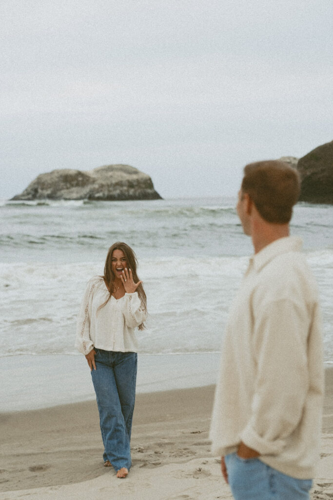 Jentrie waves at Brayden while standing barefoot on the beach