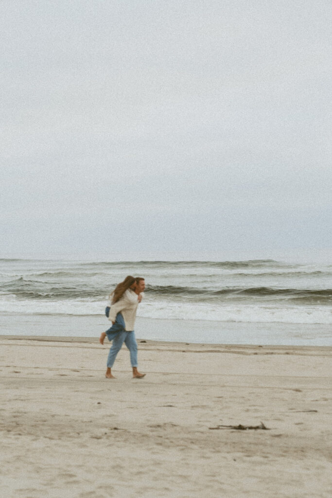 Man giving woman a piggyback ride along the beach