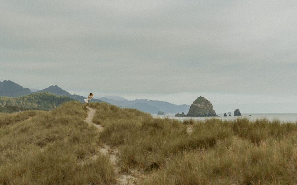 Couple embracing on a sandy dune overlooking Cannon Beach