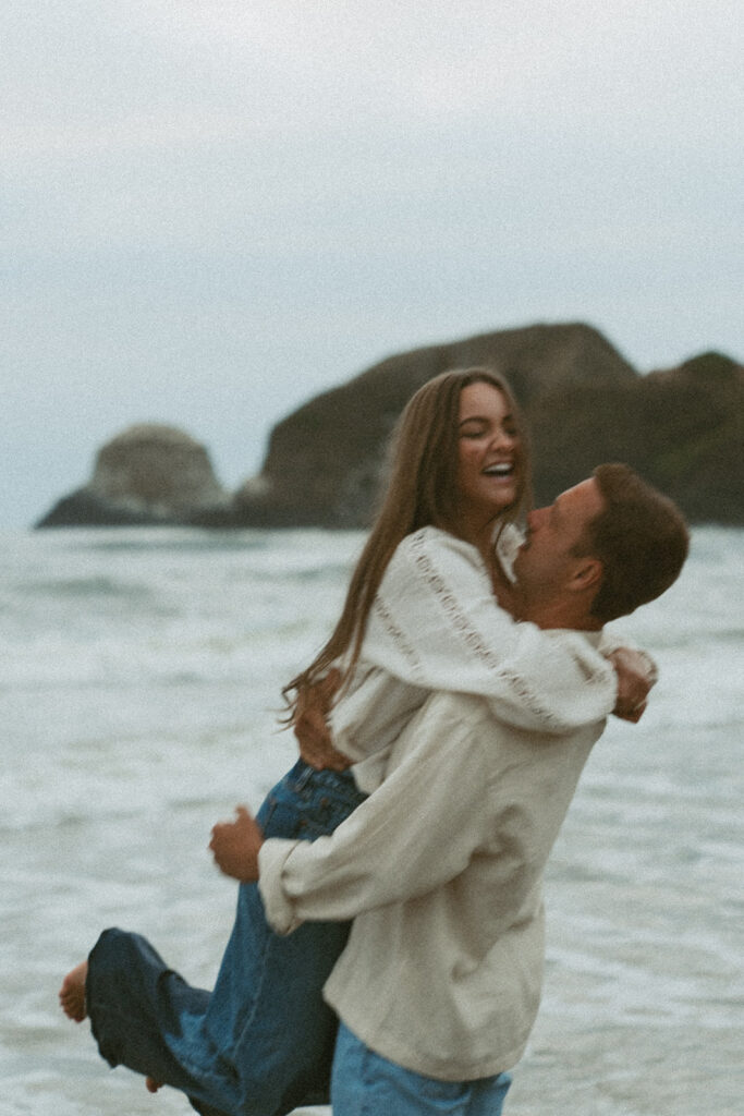 Man lifting woman and laughing together by the ocean