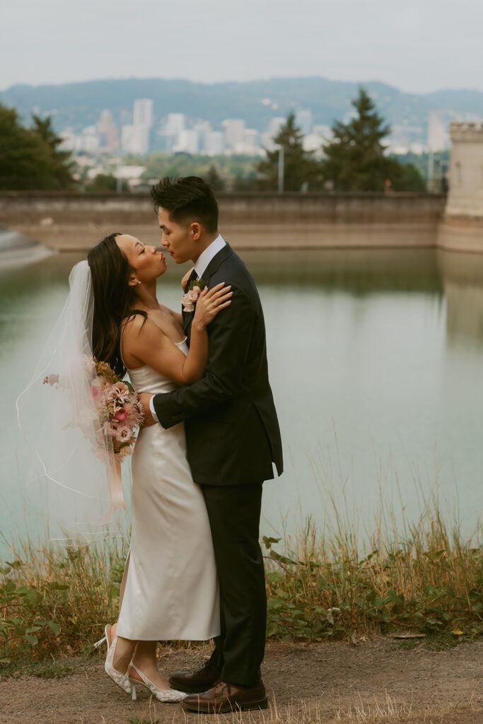 Couple kissing by waterfront Portland Oregon elopement