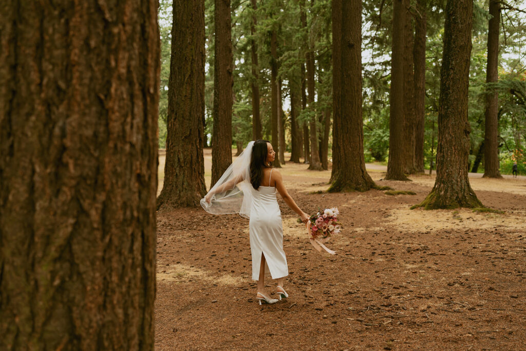 Bride twirling in her dress among tall trees at her Portland Oregon elopement