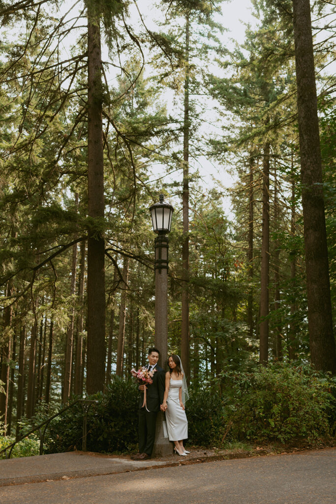 Bride and groom leaning on a light post