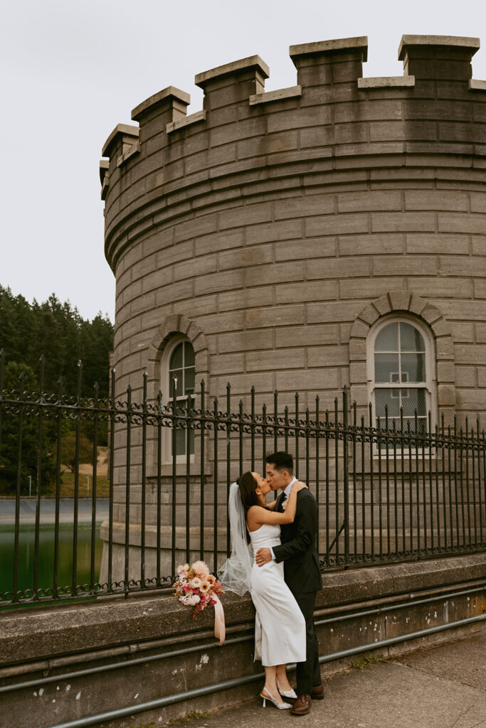 Groom embracing bride against historic architecture