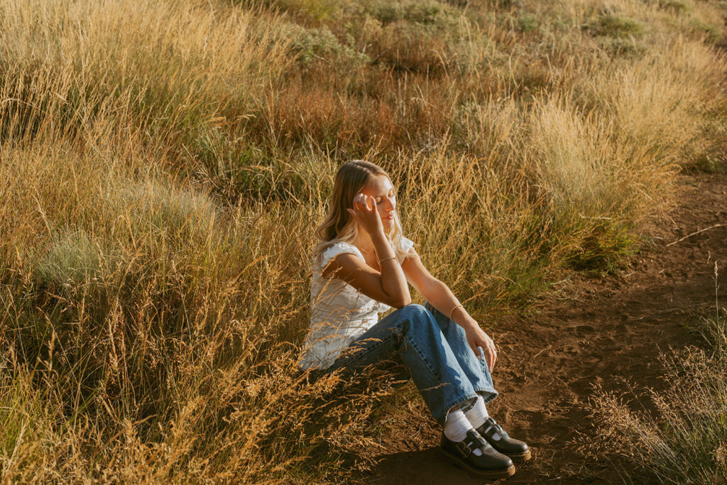 Senior girl sitting in tall grass with sunlight in Salem Oregon