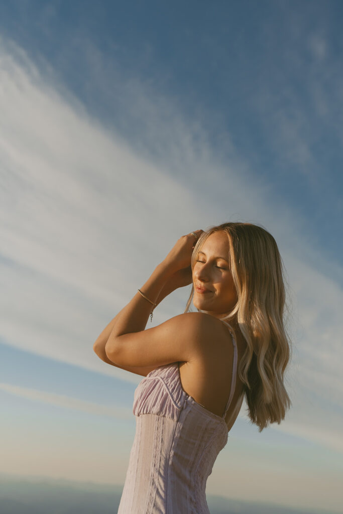 Senior girl in a lavender dress smiling with eyes closed under blue sky in Salem Oregon