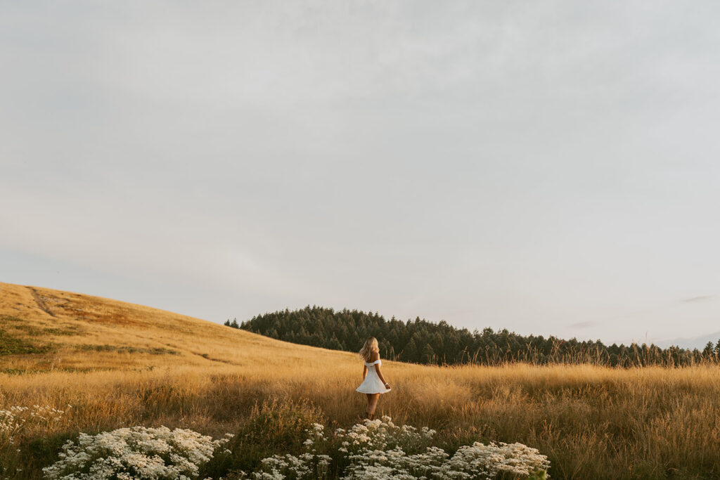 Oregon senior photography of a girl in a white dress in an open field